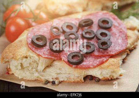 flache Pita-Brot mit Salami und Gemüse auf Holztisch Stockfoto