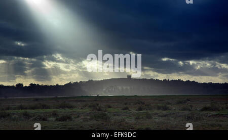 Strahl der Sonne Beleuchtung Blakeney Kirche von Cley Strand Norfolk und kommenden Sturm im winter Stockfoto