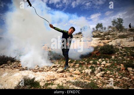 Nabi Saleh, West Bank. 6. Februar 2015. Eine palästinensische Jugend verwendet eine Schleuder wieder einen Kanister Tränengas auf israelische Truppen während der Zusammenstöße bei einer wöchentlichen Protest gegen jüdische Siedlungen im Westjordanland-Dorf von Nabi Saleh, in der Nähe von Ramallah schleudern. © Shadi Hatem/APA-Images/ZUMA Draht/Alamy Live News Stockfoto