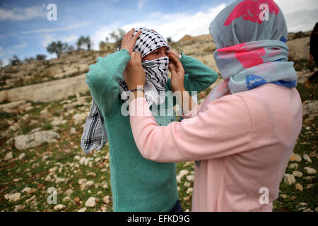 Nabi Saleh, West Bank. 6. Februar 2015. Eine weibliche palästinensische Demonstranten hilft ihrer Freundin ihr Gesicht bei Zusammenstößen mit israelischen Truppen bei einer wöchentlichen Protest gegen jüdische Siedlungen im Westjordanland-Dorf von Nabi Saleh, in der Nähe von Ramallah zu decken. © Shadi Hatem/APA-Images/ZUMA Draht/Alamy Live News Stockfoto