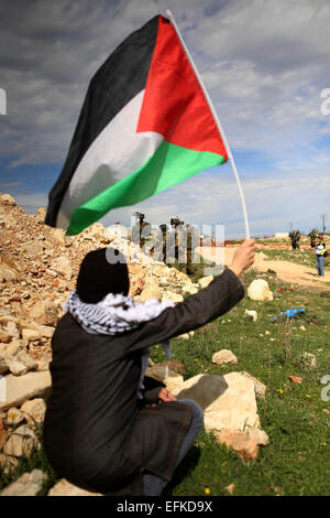 Nabi Saleh, West Bank. 6. Februar 2015. Eine Palästinenserin "Wellenlinien" eine palästinensische Flagge vor israelischen Truppen während der Zusammenstöße bei einer wöchentlichen Protest gegen jüdische Siedlungen im Westjordanland-Dorf von Nabi Saleh, in der Nähe von Ramallah. © Shadi Hatem/APA-Images/ZUMA Draht/Alamy Live News Stockfoto