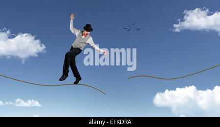 Ropewalker im schwarzen Hut stehen auf gerissene Seil in den blauen Himmel mit Wolken Stockfoto