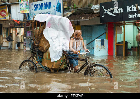 Ein Mann-Pedale eine Fahrradrikscha während Sturzflut in Monsun-Flut. Stockfoto