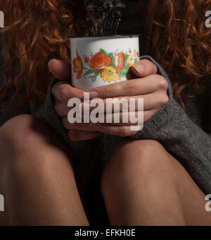 Mädchen mit warmen Pullover halten Kaffee, heiße Schokolade oder Tee. Stockfoto