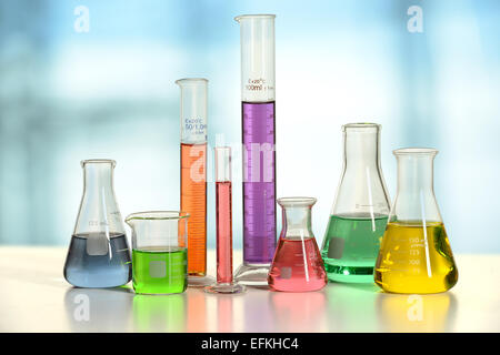 Laborglas mit Flüssigkeiten in verschiedenen Farben auf weißen Tisch - mit Beschneidungspfad auf Glas Stockfoto