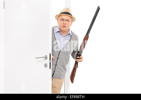 Senior mit Gewehr platzen durch eine Tür isoliert auf weißem Hintergrund Stockfoto