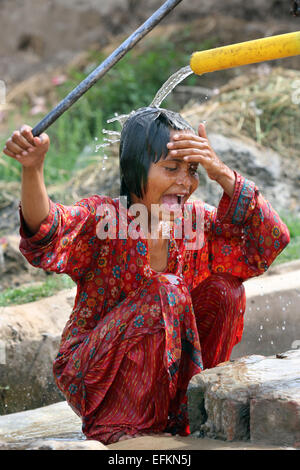 Mit einer Handpumpe ist das Mädchen den Kopf waschen. Kushpur Dorf in Pakistan Stockfoto