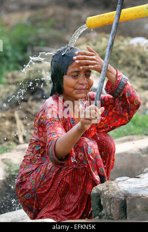 Mit einer Handpumpe ist das Mädchen den Kopf waschen. Kushpur Dorf in Pakistan Stockfoto