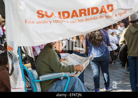Oaxaca, Mexiko - ein Schuh-Glanz-Mann liest Zeitung während des Wartens auf den Kunden an seinem Stand in der Zócalo (Hauptplatz). Stockfoto