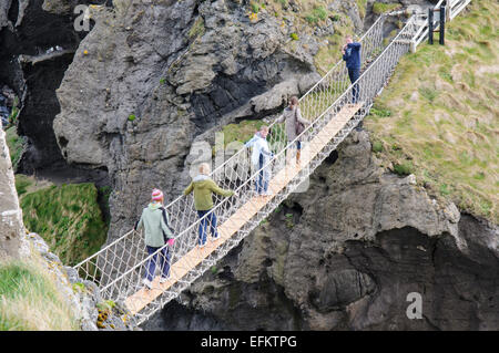 Menschen überqueren die Carrick-a-Rede rope Bridge auf der Küste von North Antrim, Nordirland. Stockfoto