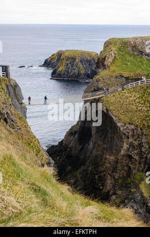 Menschen überqueren die Carrick-a-Rede rope Bridge auf der Küste von North Antrim, Nordirland. Stockfoto