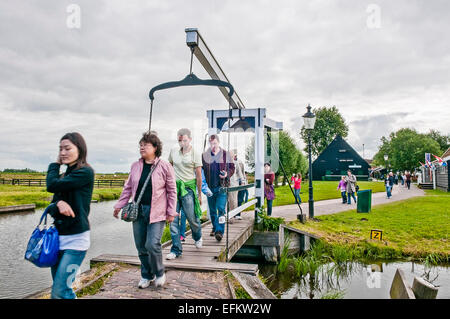 Menschen gehen über eine Fußgänger- und Zyklus Brücke über einem bewässerungskanal in Zaanse Schans, Niederlande. Stockfoto