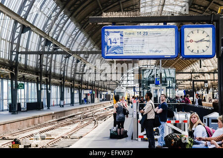 Menschen auf einer Plattform in Amsterdam Centraal Bahnhof auf einen Zug warten. Stockfoto