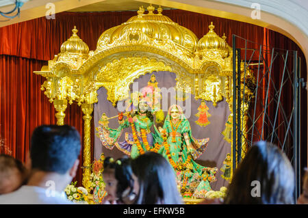 Hare-Krishna-Anhänger stehen, zu beten und Feiern vor einem Altar in einem Tempel-Raum. Stockfoto