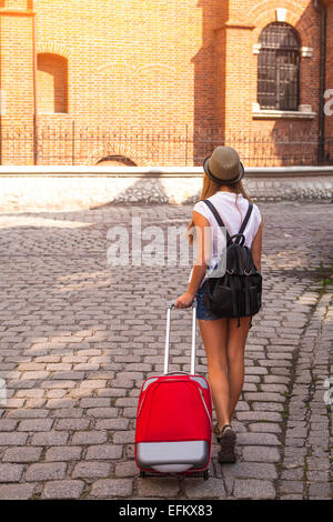 Junge süße Mädchen reist durch die Städte des alten Europa. Ein аbstract Mädchen - Rückansicht, Pflaster, roten Koffer. Stockfoto