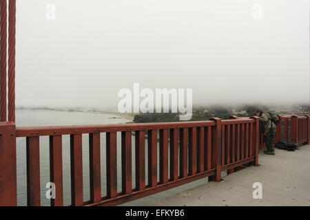 Nebligen Himmel Blick Mann schiefen Gang Geländer in Richtung Batterie Osten Bluffs und Crissy Field, Golden Gate Bridge, San Francisco, USA Stockfoto