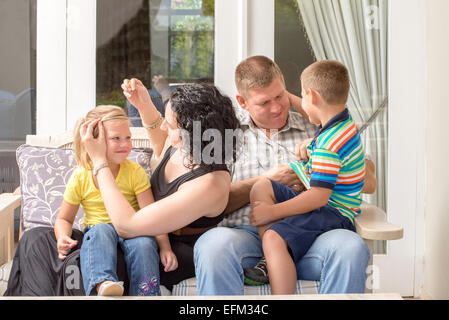 Junge Familie beisammen sitzen auf der Veranda, Spaß zu haben. Stockfoto