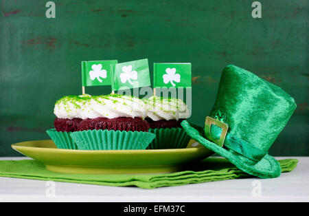 Happy St Patricks Day Cupcakes mit grünen Thema Dekorationen auf Vintage-Stil grün Holz Hintergrund. Stockfoto