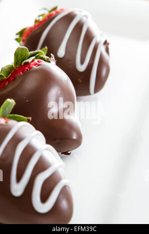 Hand getaucht Schokolade überzogene Erdbeeren auf einem weißen Teller Stockfoto