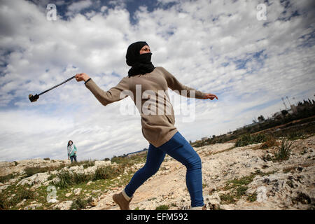 Nabi Saleh, West Bank. 6. Februar 2015. Ein maskierter weibliche Demonstrant verwendet eine Schlinge gedreht um einen Stein auf israelische Truppen während der wöchentlichen Protest gegen jüdische Siedlungen im Dorf Nabi Saleh zu schleudern. © Shadi Hatem/APA-Images/ZUMA Draht/Alamy Live News Stockfoto