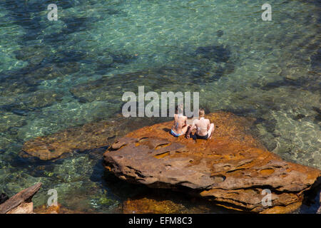 Frauen sitzen auf einem Felsen in Gordons Bay, Sydney, Australien Stockfoto