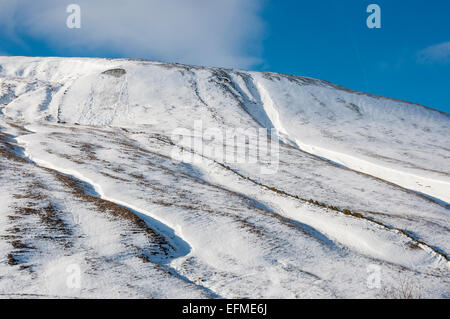 Sonnenschein auf den verschneiten Hängen der Hügel im Edale Tal, Derbyshire. Eine kleine Lawine am Hang. Stockfoto