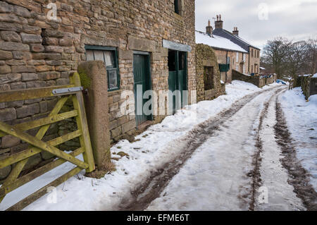 Ein Peak District Bauernhof im Winter mit Schnee bedeckt Feldweg und Steinbauten. Stockfoto