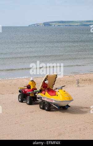 RNLI Rettungsschwimmer fährt Honda TRX Quad-Schlepper Jetski am Strand zum Meer in Bournemouth, Dorset, Großbritannien, im Juni am Meer Stockfoto