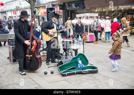 Junges Mädchen, Geld an skurrilen Straßenmusik Akt, Markt St, Manchester Stadtzentrum Stockfoto