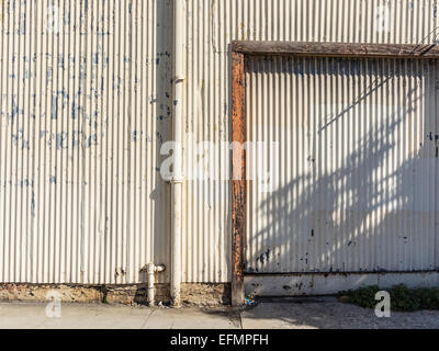 Ein Detail aus einem gut verwitterte gewellte Stahl Gebäude und das Zusammenspiel von Licht und Schatten. Stockfoto
