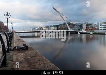 Dublins Fluss Liffey mit Samuel Beckett Bridge reflected.in das ruhige Wasser an einem bewölkten Tag. Stockfoto