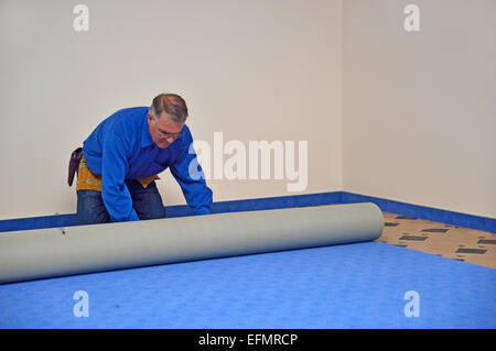 Eine Floorlayer rollt der neue Teppich in einem Job Bodenverlegung Stockfoto