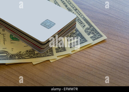 Ein Batch Kredit- oder EC-Karten und ein paar Dollar-Noten auf einem Holztisch Stockfoto
