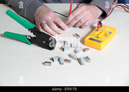Hände mit einem digitalen multimeter Tester einen RJ45-Anschluss testen Stockfoto