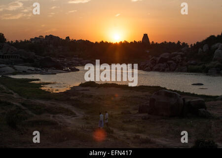 (150208)--KARNATAKA, 8. Februar 2015 (Xinhua)--Dorfbewohner gehen, wenn die Sonne in Hampi im Bellary District of India Bundesstaat Karnataka, 6. Februar 2015 untergeht. Spitznamen wie "Hampi: The Lost World", die strenge, grandiose Website von Hampi war die letzte Hauptstadt des letzten großen hinduistischen Königreich von Vijayanagar. Seine sagenhaft reichen Fürsten gebaut dravidischen Tempel und Paläste, die die Bewunderung der Reisenden zwischen dem 14. und 16. Jahrhundert. Von der Deccan muslimischen Konföderation im Jahre 1565 erobert, wurde die Stadt über einen Zeitraum von sechs Monaten vor dem Verlassenwerden geplündert. Die Gruppen der Monumente in Hampi war Stockfoto