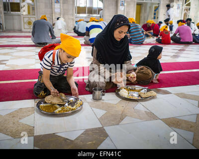 Bangkok, Bangkok, Thailand. 8. Februar 2015. Eine muslimische Frau und ihren Kindern beenden ihr Frühstück während der Gemeinschaft Mahlzeit an der Sikh-Tempel in Bangkok. Thailand hat eine kleine, aber einflussreiche Sikh-Gemeinde. Sikhs kamen nach Thailand, dann Siam in den 1890er Jahren. Mittlerweile gibt es mehrere tausend Thai-indische Sikh-Familien. Die Sikh-Tempel in Bangkok, Gurdwara Siri Guru Singh Sabha, wurde 1913 gegründet. Das heutige Gebäude, angrenzend an das Original Gurdwara ("Tor zum Guru''), wurde im Jahr 1979 gebaut. Die Sikh-Gemeinschaft dient eine tägliche kostenlose vegetarische Mahlzeit in der Gurdwara, die availabl Stockfoto