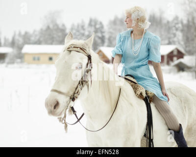 Attraktive Frau mit blauen Kleid und sie auf einem weißen Pferd Stockfoto