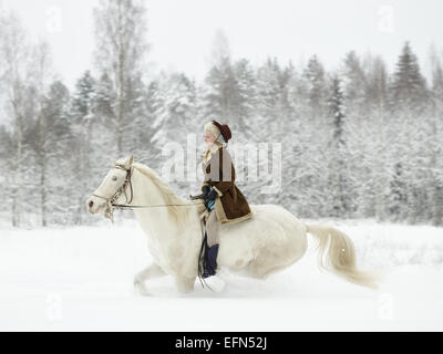Attraktive Frau Reiten ein weißes Pferd, Winterlandschaft Stockfoto