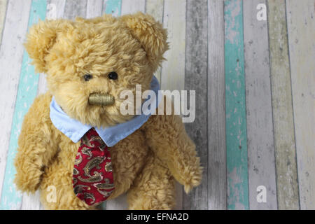 Büro-Teddybär bekleidet mit Hemd und Krawatte vor einem rustikalen hölzernen Hintergrund. Stockfoto