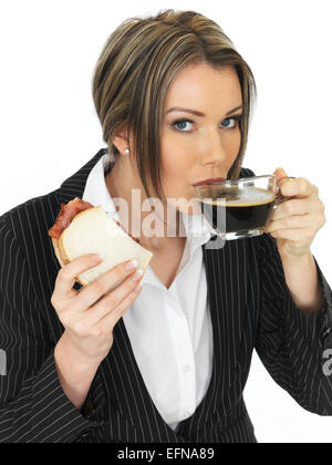 Selbstbewussten Jungen Business Frau trinkt eine Tasse starken Espresso Essen ein Sandwich Isoliert gegen einen weißen Hintergrund mit einen Freistellungspfad Stockfoto