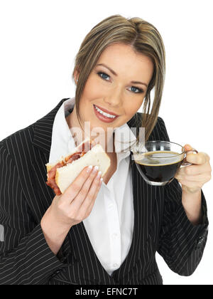 Selbstbewussten Jungen Business Frau trinkt eine Tasse starken Espresso Essen ein Sandwich Isoliert gegen einen weißen Hintergrund mit einen Freistellungspfad Stockfoto