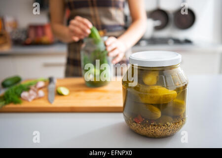 Closeup auf Glas mit marinierten Gurken auf Tisch und Hausfrau Beizen im Hintergrund Stockfoto