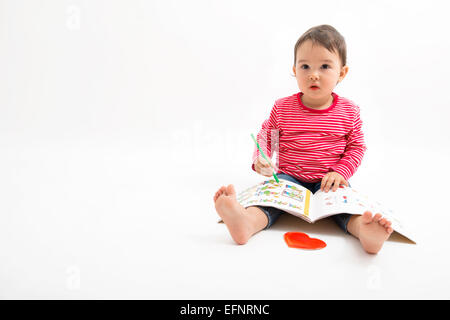 kleines Mädchen zieht auf dem Boden sitzend Stockfoto