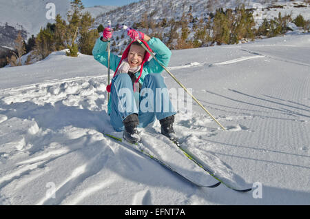 Junges Mädchen mit roten Wintermütze hebt nach dem Sturz im nordischen Ski Resort von Tal Azun im hohen Pyrenäen, Stockfoto