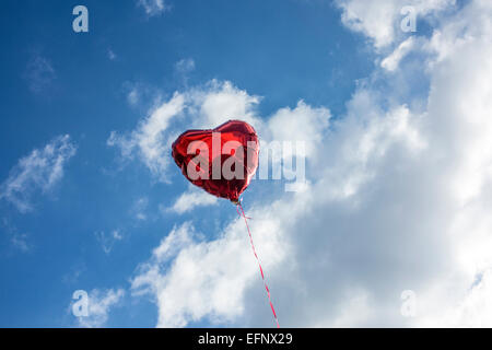 Ein rotes Herz geformt Helium-Ballon in einem blauen Wolkenhimmel Stockfoto