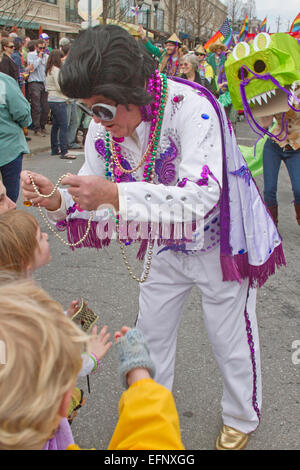 Ein bunter kostümierter Elvis Charakter verleiht Karneval Perlen für Kinder in der Feder Karneval Parade in der Innenstadt von Asheville, NC Stockfoto