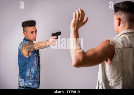 Junger Mann mit einer Pistole auf einen anderen Kerl Stockfoto