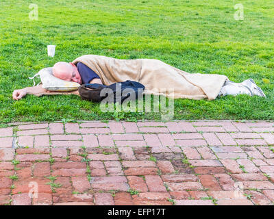 Ein Obdachloser schläft liegen außen auf dem Rasen vor dem Rathaus in Santa Barbara, Kalifornien. Stockfoto