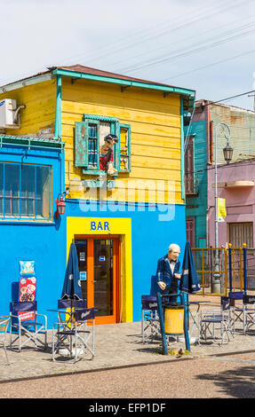 Farbenfrohe bar Gebäude in La Boca, Buenos Aires, Argentinien mit Bildnissen von einem Butler außerhalb und eine Frau aus dem Fenster gelehnt Stockfoto