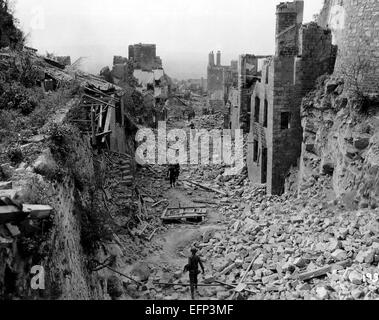 US-Armeesoldaten bewegen durch Schutt und Geröll, wie sie vorher gegen Deutschland Truppen während der Schlacht um die Normandie 6. August 1944 in Domfront, Orne, Normandie, Frankreich zu fliehen. Stockfoto